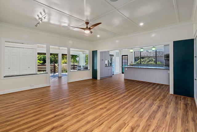 unfurnished living room with crown molding, wood-type flooring, ceiling fan, and plenty of natural light