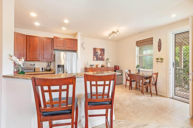 24 One Hali Ln Unit 7-203, Kihei, HI 96753 - kitchen featuring stainless steel fridge with ice dispenser, light stone counters, recessed lighting, a peninsula, and a breakfast bar