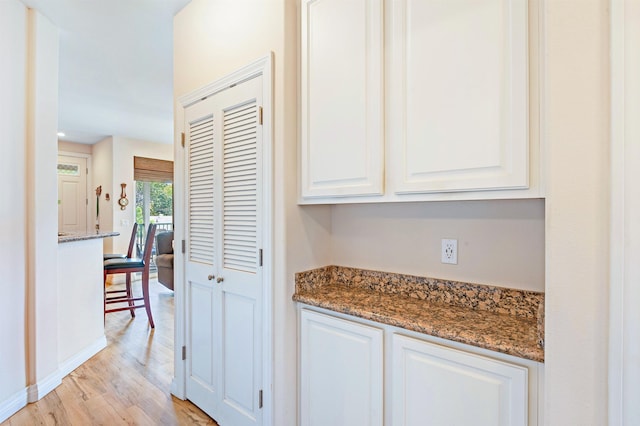 24 One Hali Ln Unit 7-203, Kihei, HI 96753 - kitchen with light wood finished floors, white cabinetry, stone counters, and baseboards
