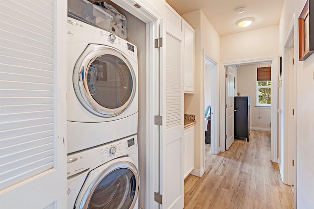 24 One Hali Ln Unit 7-203, Kihei, HI 96753 - washroom with stacked washer / dryer, light wood-style floors, and baseboards