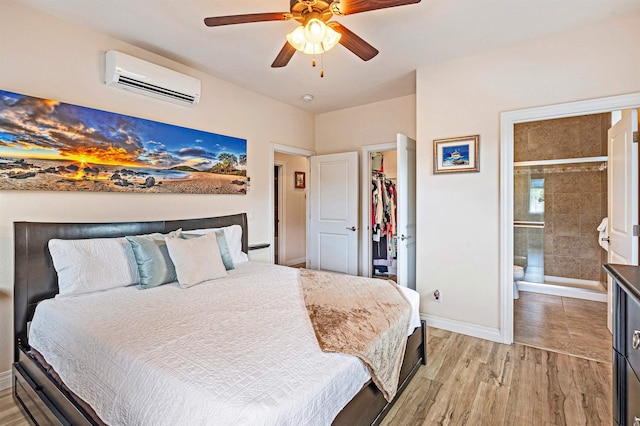 24 One Hali Ln Unit 7-203, Kihei, HI 96753 - bedroom with a wall unit AC, light wood-type flooring, a walk in closet, baseboards, and ensuite bath