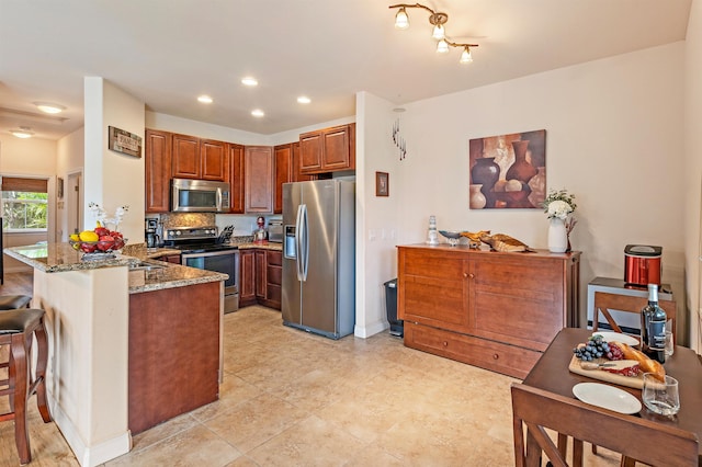 24 One Hali Ln Unit 7-203, Kihei, HI 96753 - kitchen with appliances with stainless steel finishes, a peninsula, stone counters, a kitchen bar, and brown cabinetry
