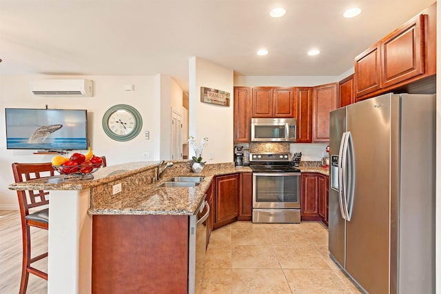 24 One Hali Ln Unit 7-203, Kihei, HI 96753 - kitchen featuring appliances with stainless steel finishes, a sink, a wall mounted AC, a peninsula, and light stone countertops
