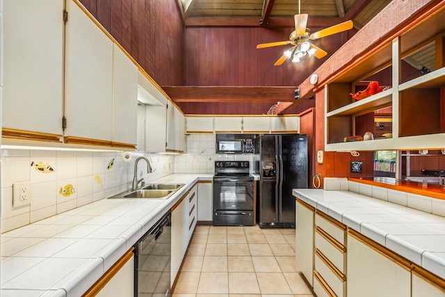 kitchen with sink, black appliances, light tile patterned floors, tile countertops, and white cabinets