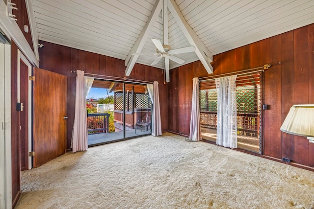 interior space featuring lofted ceiling with beams, light colored carpet, ceiling fan, and wood walls