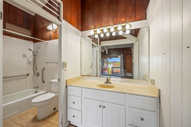 full bathroom featuring tile patterned floors, vanity, toilet, tiled shower / bath, and wood walls