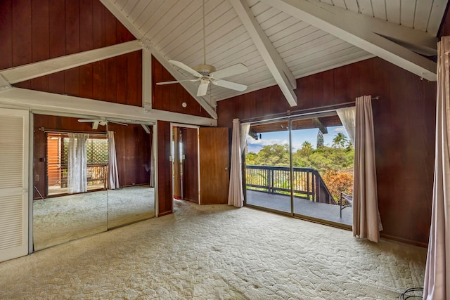 interior space featuring carpet flooring, wood walls, ceiling fan, and beam ceiling