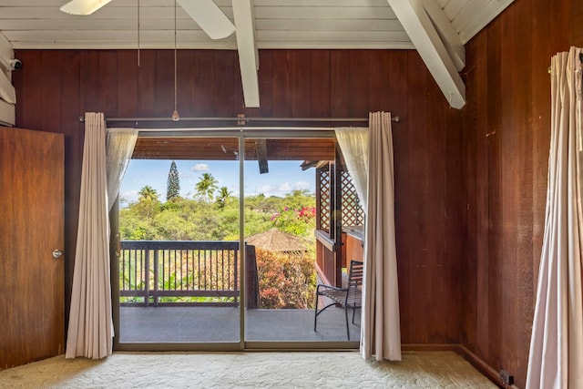 doorway to outside featuring beamed ceiling, ceiling fan, and wooden walls