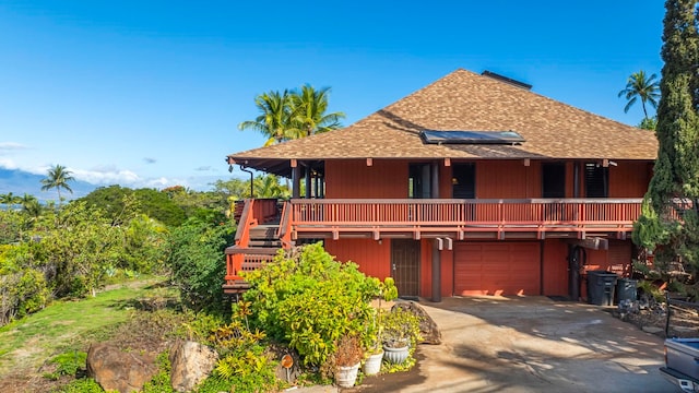 rear view of property with a garage and solar panels