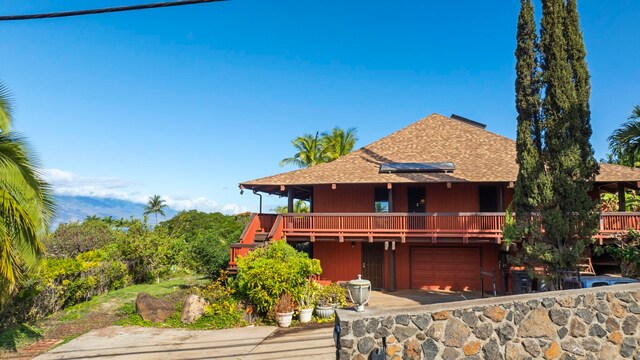 view of front of property with a wooden deck, a garage, and solar panels