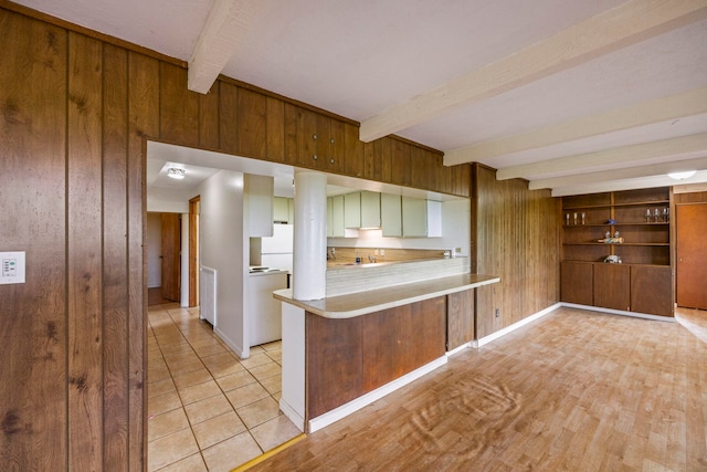 kitchen with kitchen peninsula, wooden walls, beam ceiling, white fridge, and light tile patterned flooring