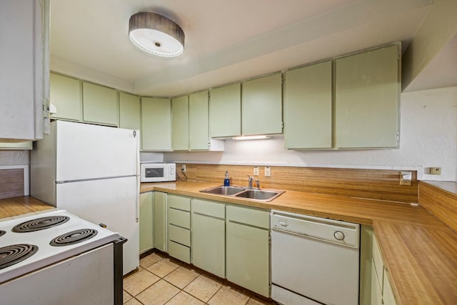 kitchen with sink, light tile patterned floors, white appliances, and green cabinetry