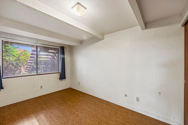 unfurnished room featuring beamed ceiling and hardwood / wood-style flooring