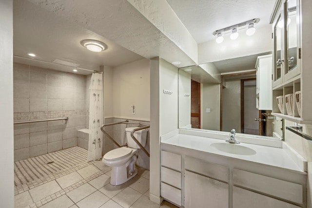 bathroom with vanity, a textured ceiling, tile walls, tile patterned flooring, and toilet