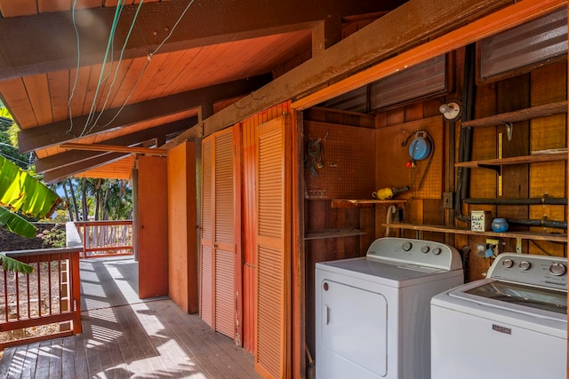 clothes washing area featuring hardwood / wood-style flooring, washer and clothes dryer, wooden ceiling, and wooden walls