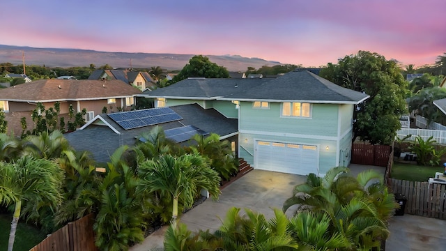 view of front of property with a garage, solar panels, and a mountain view