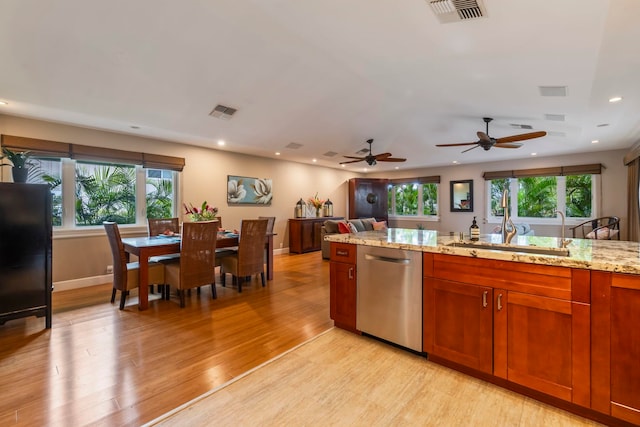 kitchen with a healthy amount of sunlight, light stone counters, dishwasher, and light hardwood / wood-style flooring