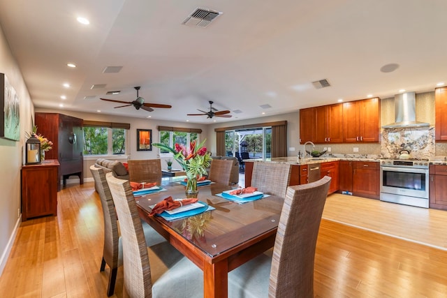 dining space with ceiling fan, sink, and light hardwood / wood-style flooring