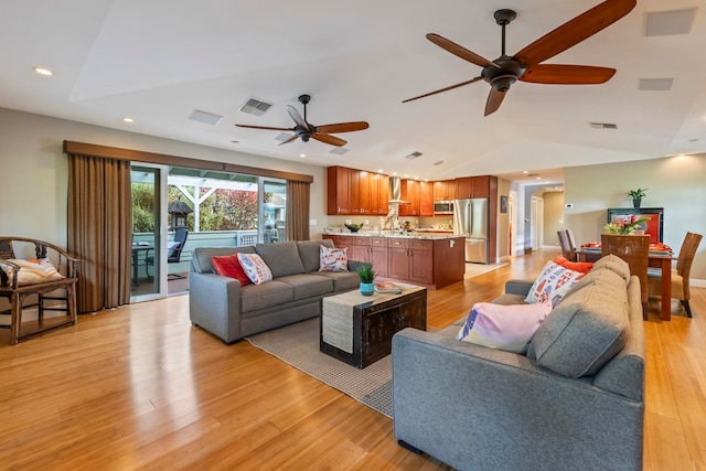 living room featuring light hardwood / wood-style floors, lofted ceiling, and ceiling fan