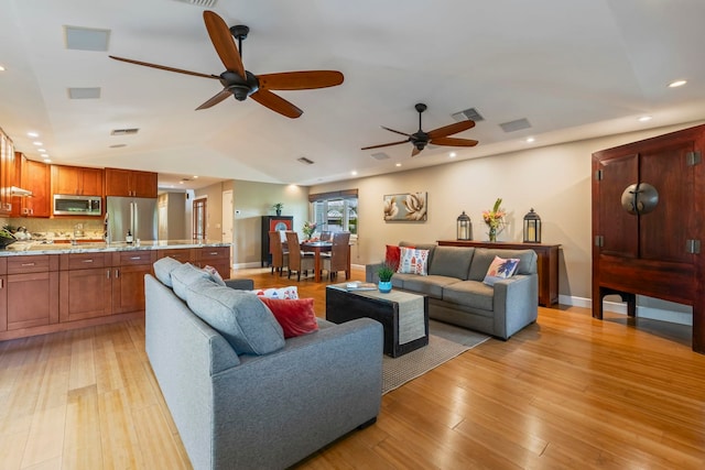 living room with vaulted ceiling, ceiling fan, and light hardwood / wood-style flooring