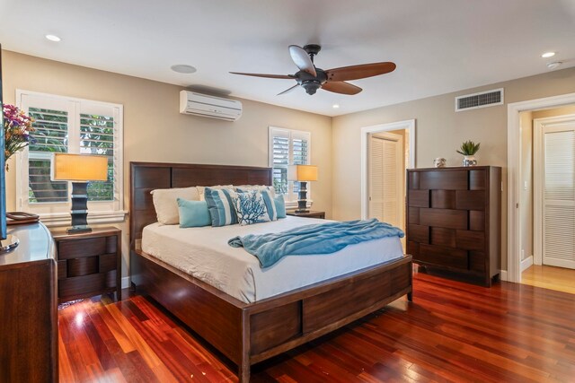 bedroom with dark hardwood / wood-style flooring, a closet, a wall unit AC, and ceiling fan