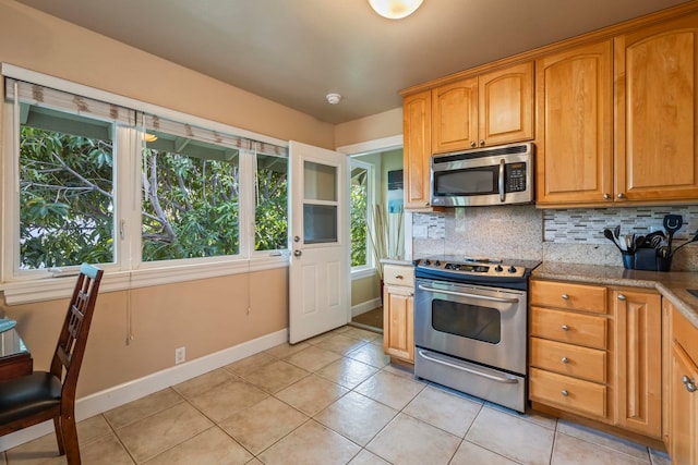 kitchen featuring backsplash, light stone countertops, light tile patterned flooring, and stainless steel appliances