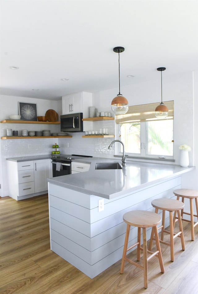 kitchen featuring sink, stainless steel appliances, pendant lighting, a breakfast bar, and white cabinets