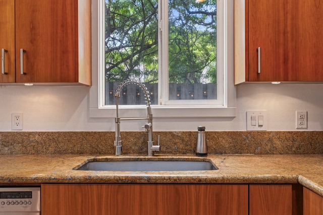 kitchen with sink, plenty of natural light, stainless steel dishwasher, and light stone counters