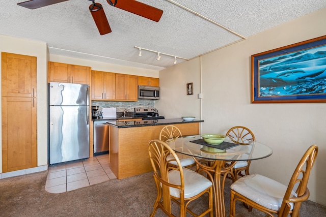 2495 S Kihei Rd Unit 248, Kihei, HI 96753 - kitchen featuring appliances with stainless steel finishes, a ceiling fan, backsplash, dark countertops, and brown cabinets