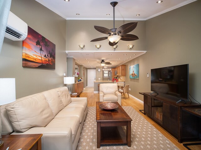 living room featuring a wall mounted AC, light wood-type flooring, ornamental molding, and ceiling fan