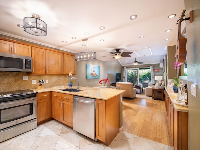 kitchen with stainless steel appliances, a peninsula, a sink, open floor plan, and brown cabinetry