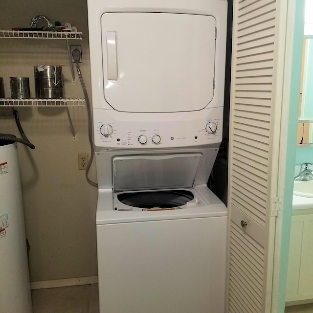 laundry area featuring stacked washer and dryer, sink, and water heater