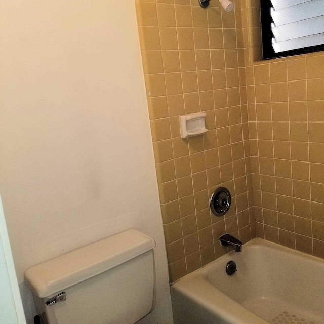 bathroom with toilet and tiled shower / bath combo