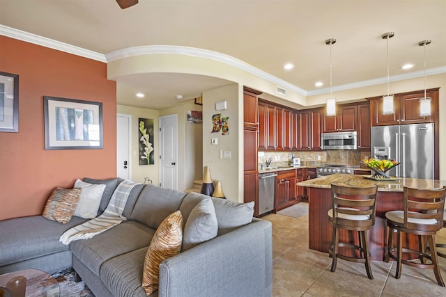 kitchen with appliances with stainless steel finishes, a breakfast bar, decorative light fixtures, open floor plan, and decorative backsplash