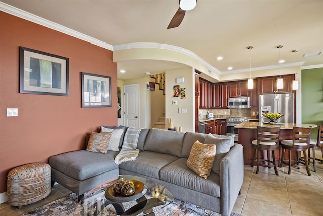 living area with ceiling fan, visible vents, light tile patterned floors, stairway, and ornamental molding