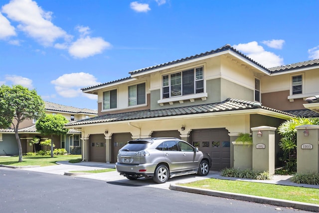 view of front of house featuring stucco siding, concrete driveway, a tile roof, and a garage