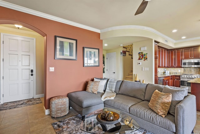living room featuring arched walkways, a ceiling fan, stairway, and ornamental molding