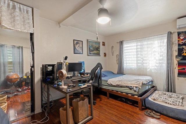 bedroom with ceiling fan, a wall unit AC, and wood-type flooring