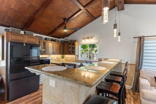 kitchen featuring black refrigerator, wood ceiling, beam ceiling, light stone countertops, and pendant lighting