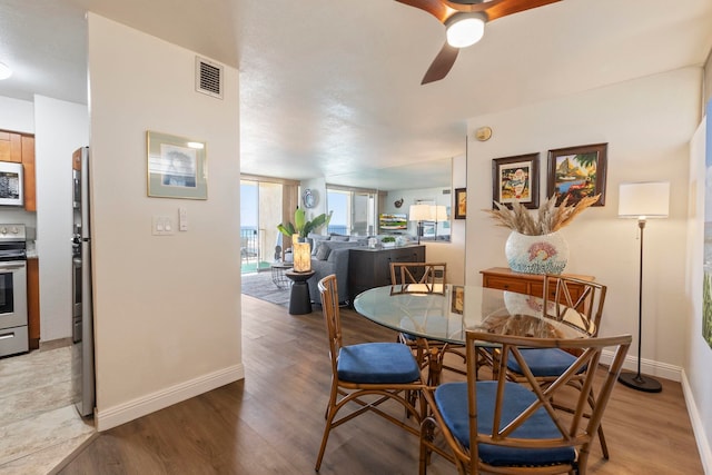 dining room with a ceiling fan, baseboards, and light wood-style flooring