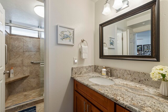 full bathroom with a tile shower and vanity