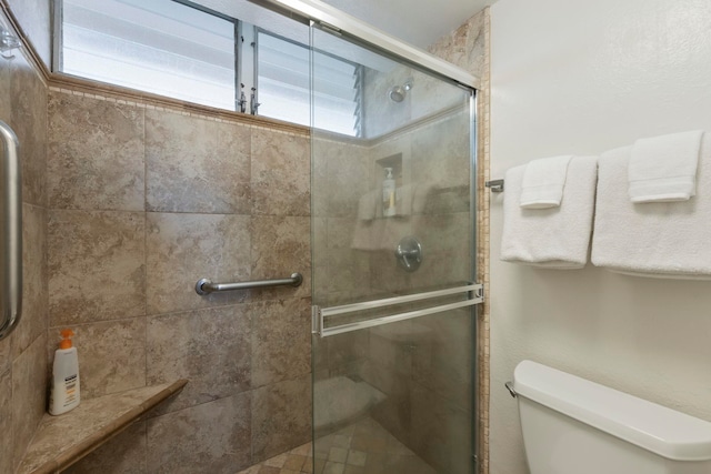 bathroom featuring a shower stall and toilet