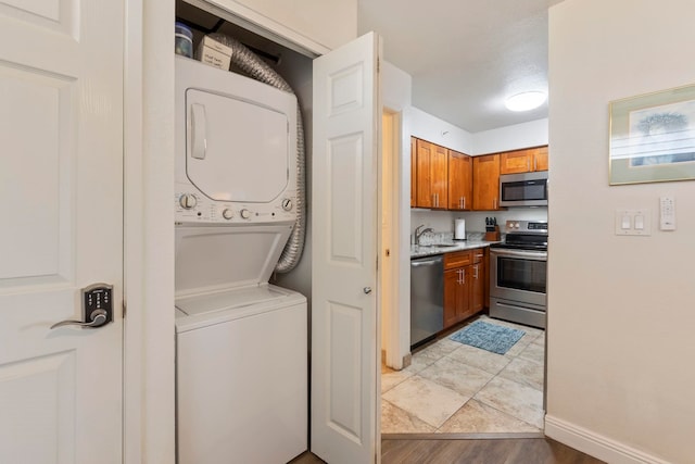 washroom with stacked washer and clothes dryer, light wood-style flooring, and baseboards