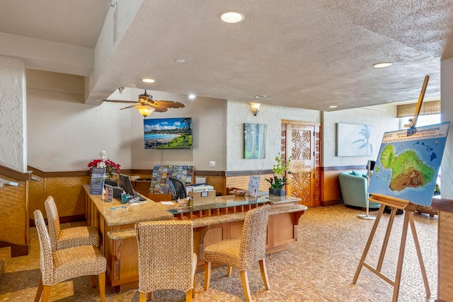 lobby featuring recessed lighting, a textured wall, a textured ceiling, and a wainscoted wall