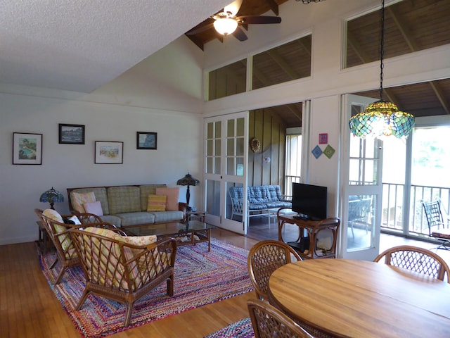 living room with ceiling fan, light hardwood / wood-style floors, vaulted ceiling, and a textured ceiling