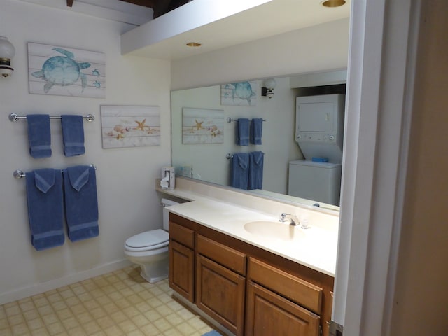 bathroom with stacked washing maching and dryer, toilet, tile floors, and vanity with extensive cabinet space