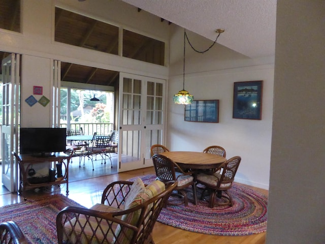 dining room with lofted ceiling, light hardwood / wood-style flooring, and a textured ceiling