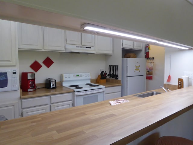 kitchen featuring white appliances, wood counters, and white cabinetry