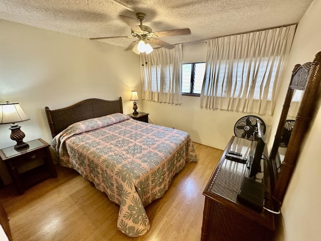 bedroom with a textured ceiling, light hardwood / wood-style flooring, and ceiling fan