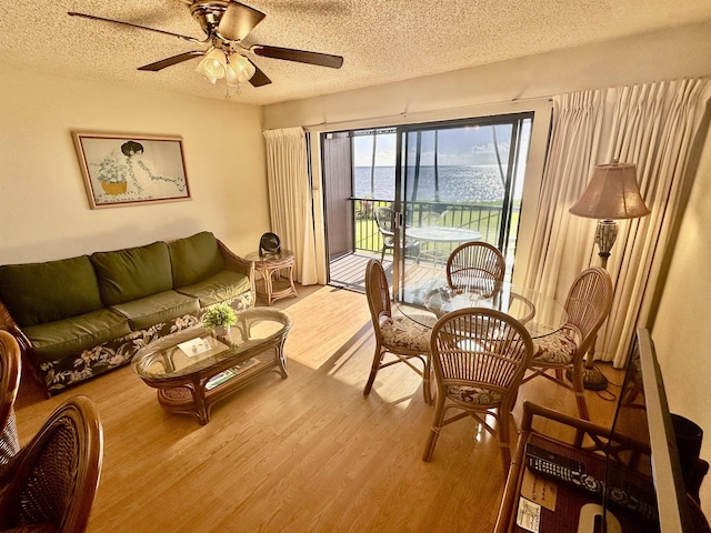 interior space featuring ceiling fan, a water view, light hardwood / wood-style floors, and a textured ceiling